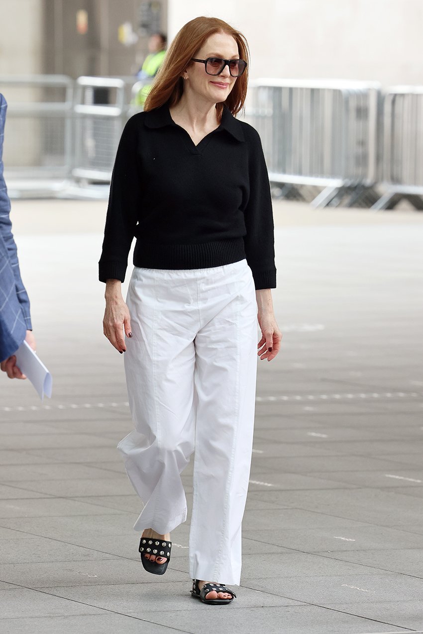 Julianne Moore wearing a black top, white pants, and sunglasses in London