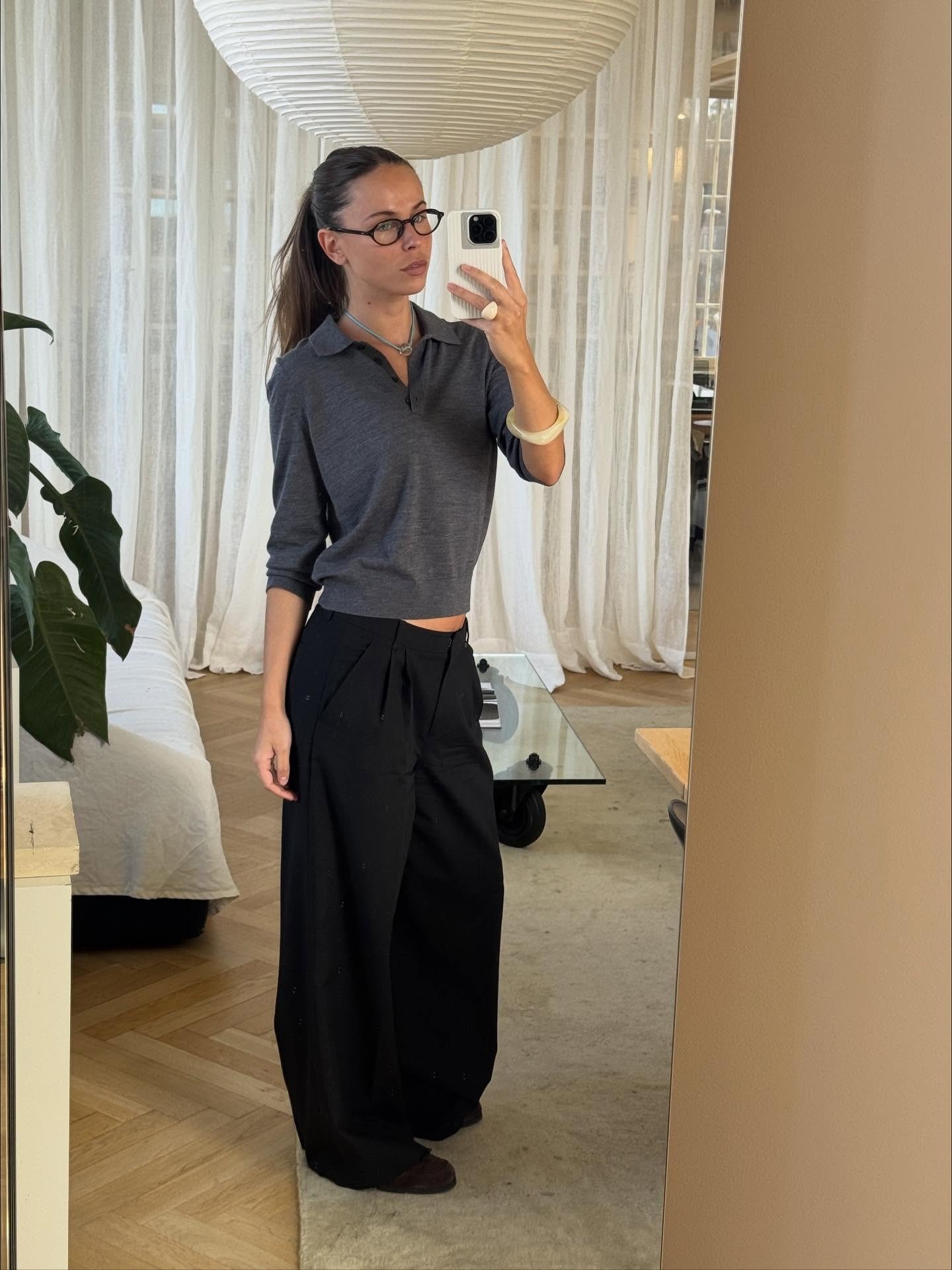 Johanna Lager wears black wide-leg trousers with a dark grey polo sweater.