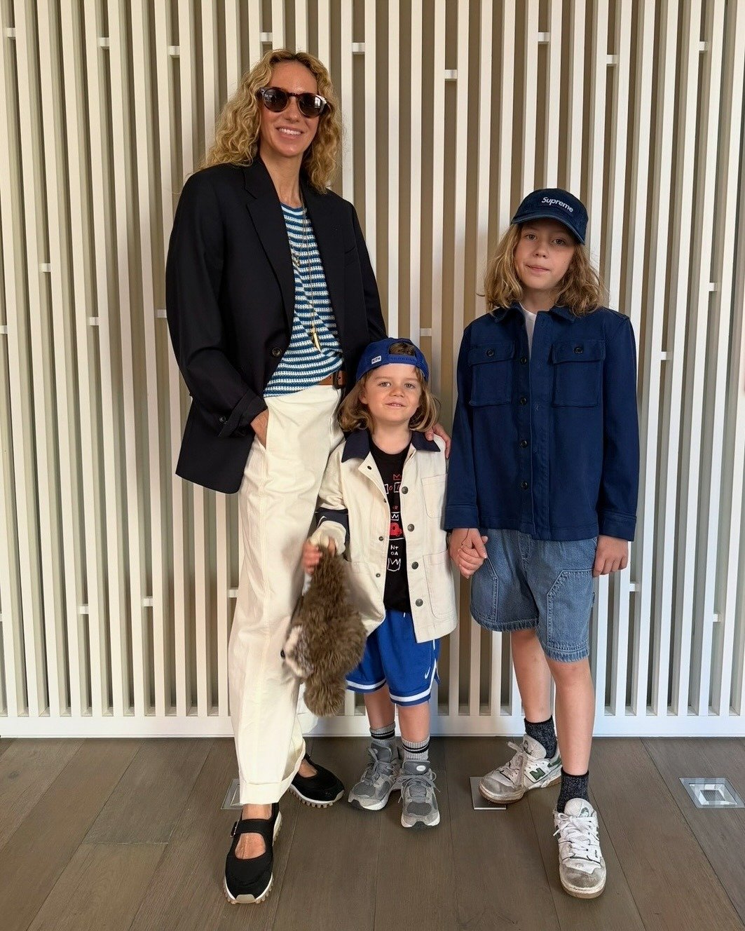 Olympia wears a stripe shirt, black blazer, white pants, and mary jane sneakers.